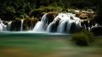 A waterfall cascading over a rocky terrain surrounded by dense greenery.