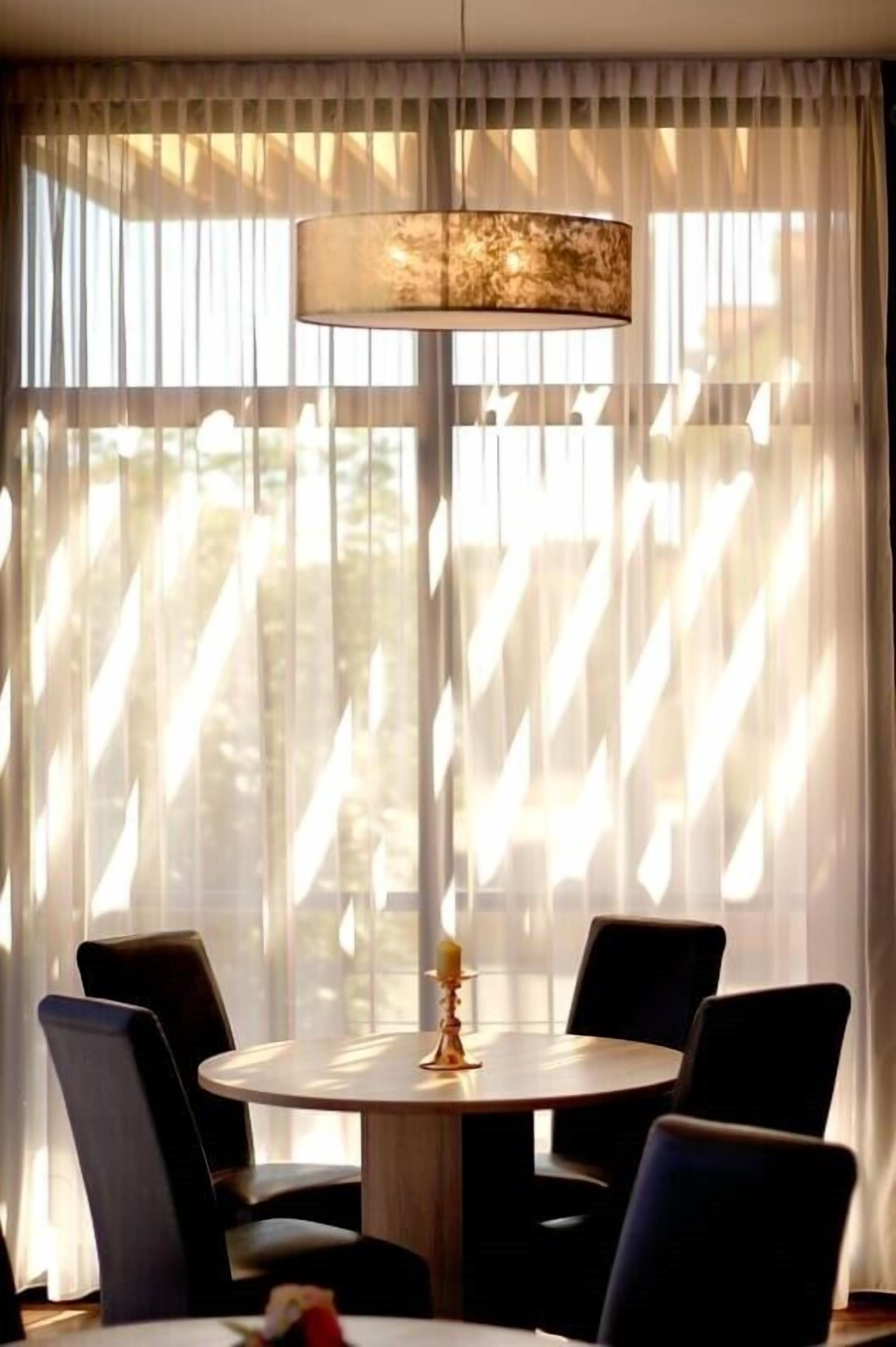 Un espace repas avec une table ronde, des chaises noires et un luminaire suspendu.