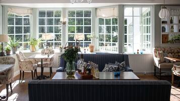 Una habitación acogedora con un amplio ventanal, un sofá, una mesa de comedor y varias plantas en macetas.