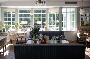 Una habitación acogedora con un amplio ventanal, un sofá, una mesa de comedor y varias plantas en macetas.
