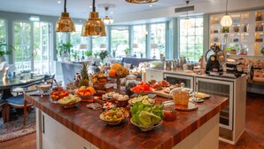 Une cuisine bien éclairée, avec un îlot central en bois rempli de divers aliments et ustensiles de cuisine.