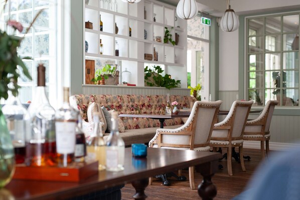 Un comedor con una mesa y sillas de madera, un banco floral y estantes con diversos objetos.
