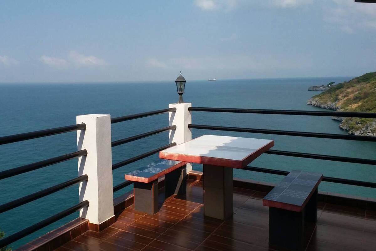 A terrace with a table and benches overlooking the sea.