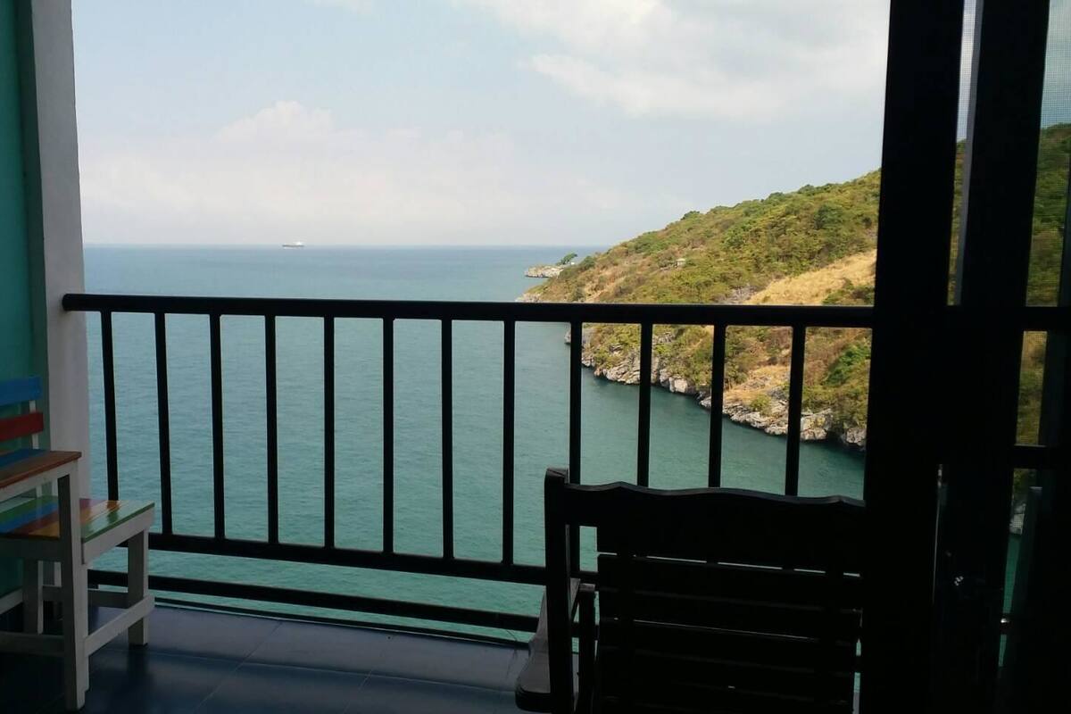 A balcony with a view of the sea and a rocky hillside.
