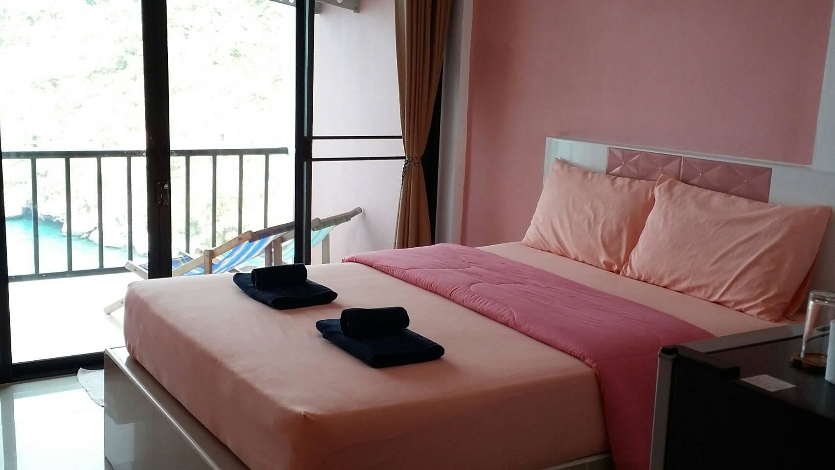A hotel room with a bed, a nightstand, a window with a view of a pool, and a balcony.