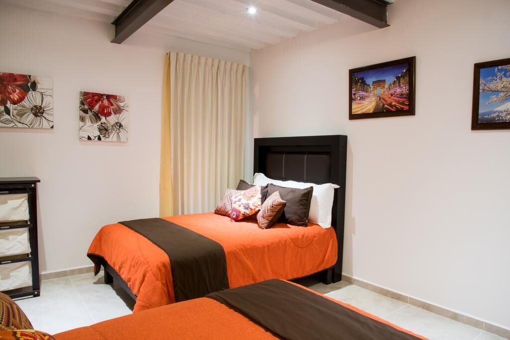 A hotel room with two beds, a nightstand, and artwork on the walls.
