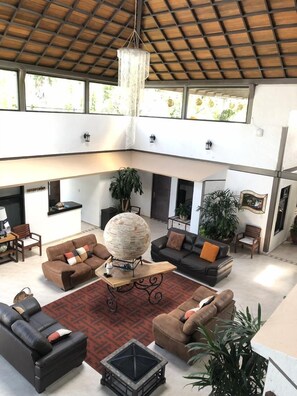 A spacious living area with multiple sofas, a large decorative globe, and potted plants. - Vista Real Villas (Corregidora)