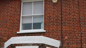 A red brick house with a white window and door, a small balcony, and a chimney. - Victoria House (Colchester)