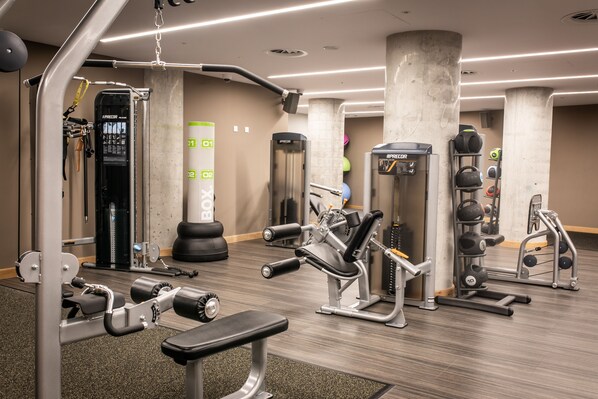 A gym with various exercise equipment, including weight machines, a bench, and free weights. - Lincoln Plaza London, Curio Collection by Hilton (London)