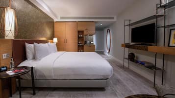 A hotel room with a large bed, a TV, a desk, and a bookshelf.