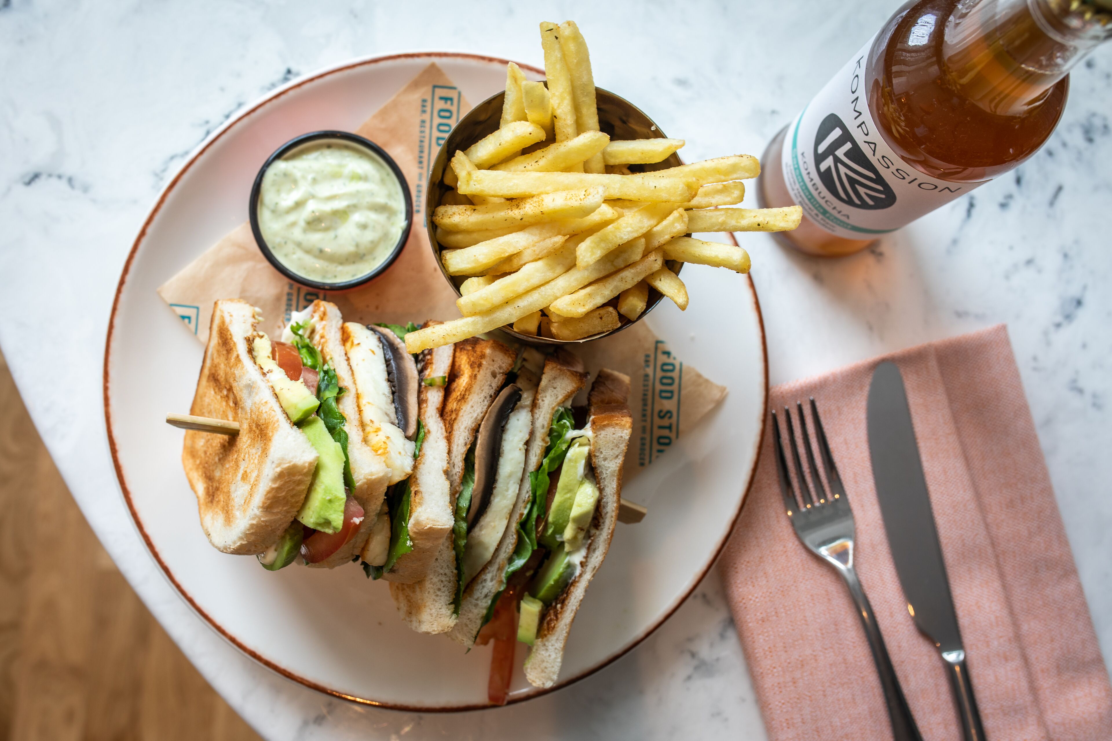 Une assiette avec un sandwich, des frites et une boisson.