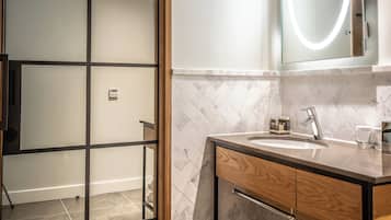 Un baño moderno con puerta de vidrio, tocador con espejo y perchero.