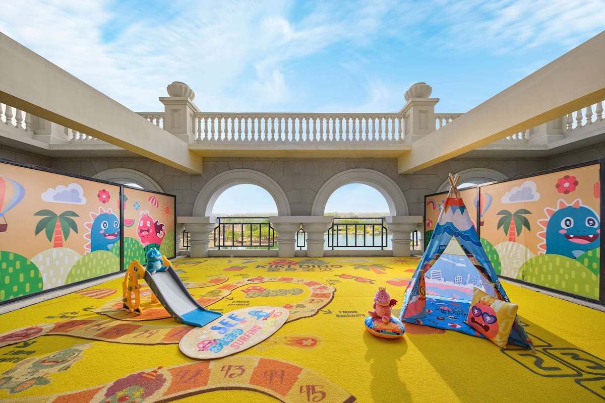 Ein Kinderspielbereich mit Rutsche, Hüpfburgen und bunten Wandmalereien.