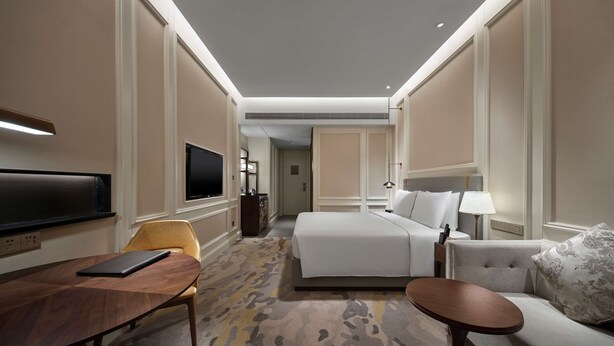 A hotel room with a bed, a sofa, a TV, a desk, and a chair. - Hollick Hotel Wen'an, Tapestry Collection by Hilton (Langfang)