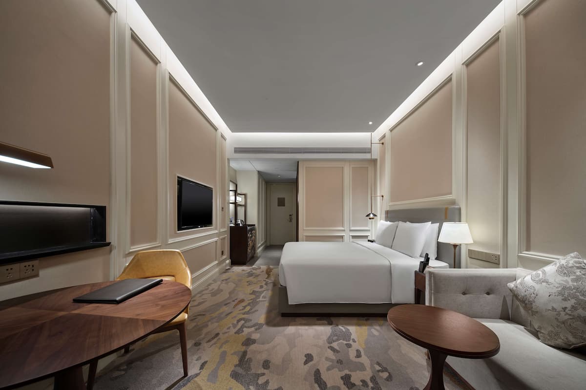 Ein Hotelzimmer mit einem Bett, einer Couch, einem Fernseher, einem Schreibtisch und einem Sessel.
