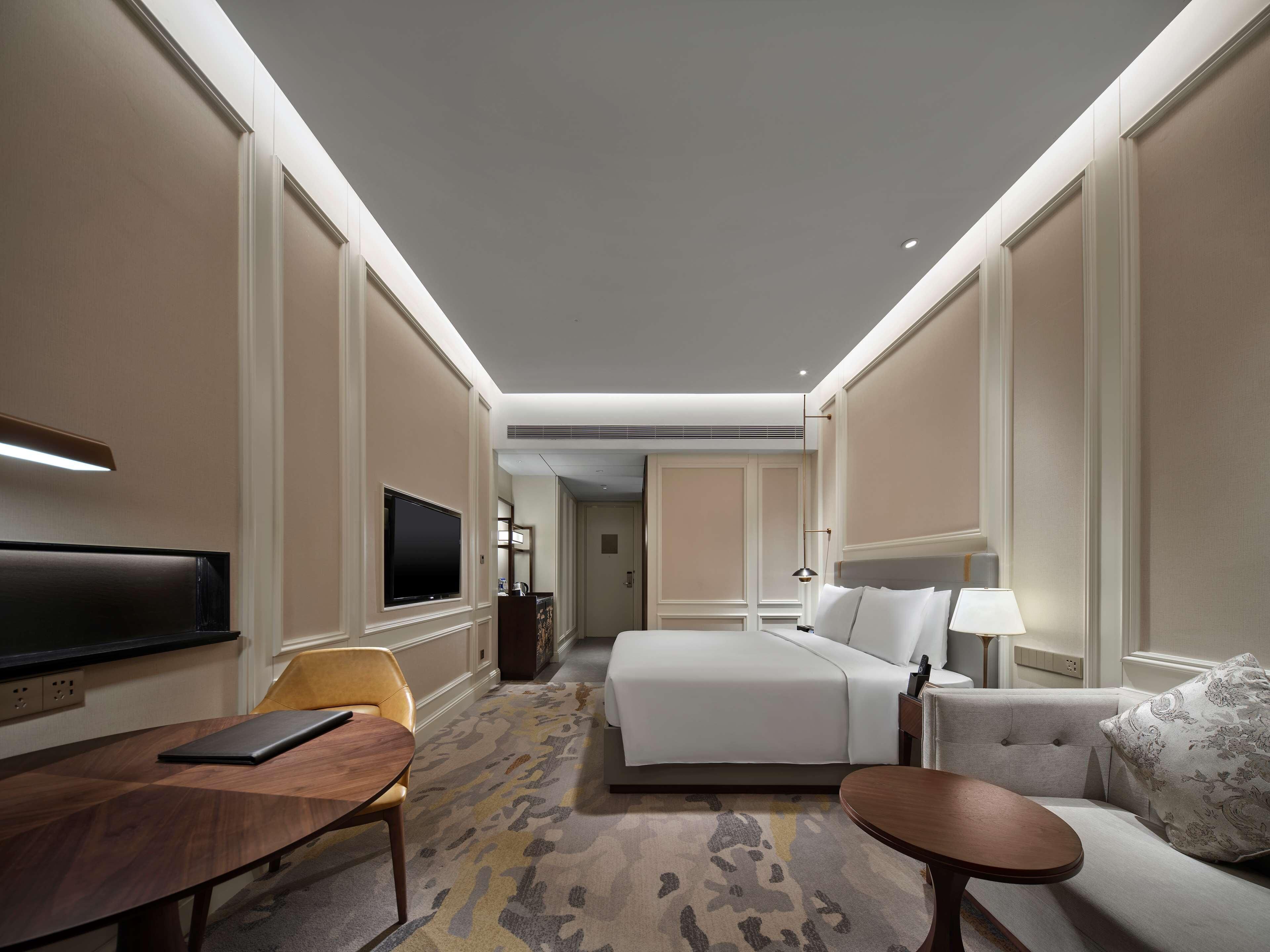 Een hotelkamer met een bed, een bank, een televisie, een bureau en een stoel.