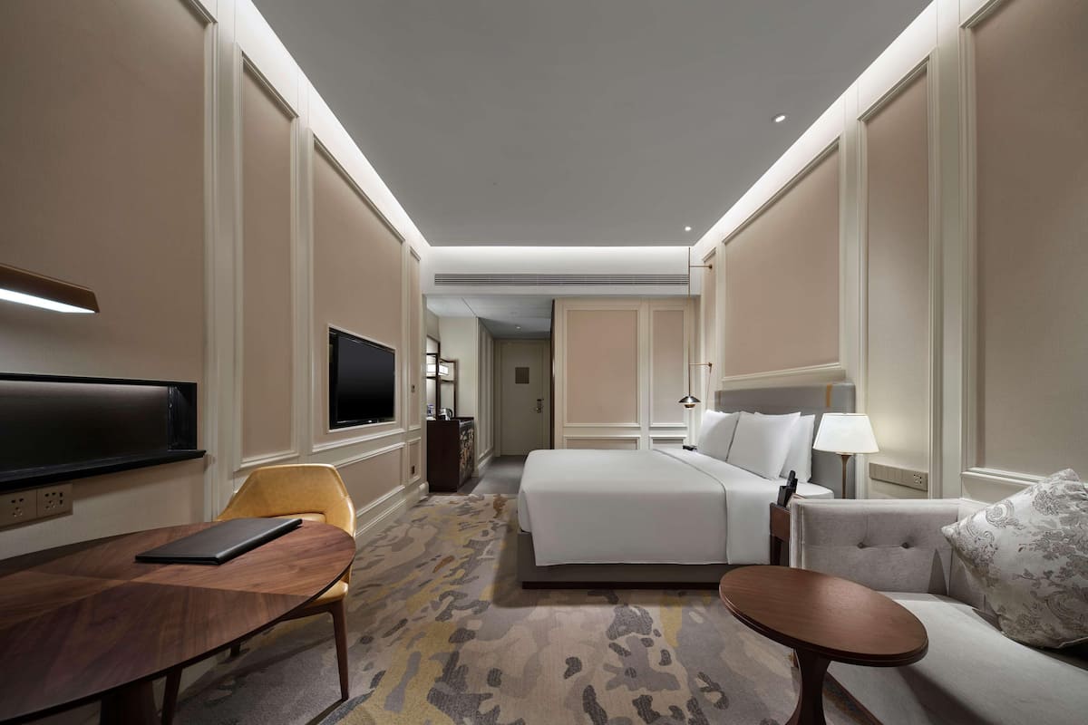 Ein Hotelzimmer mit Bett, Sofa, Fernseher, Schreibtisch und Stuhl.