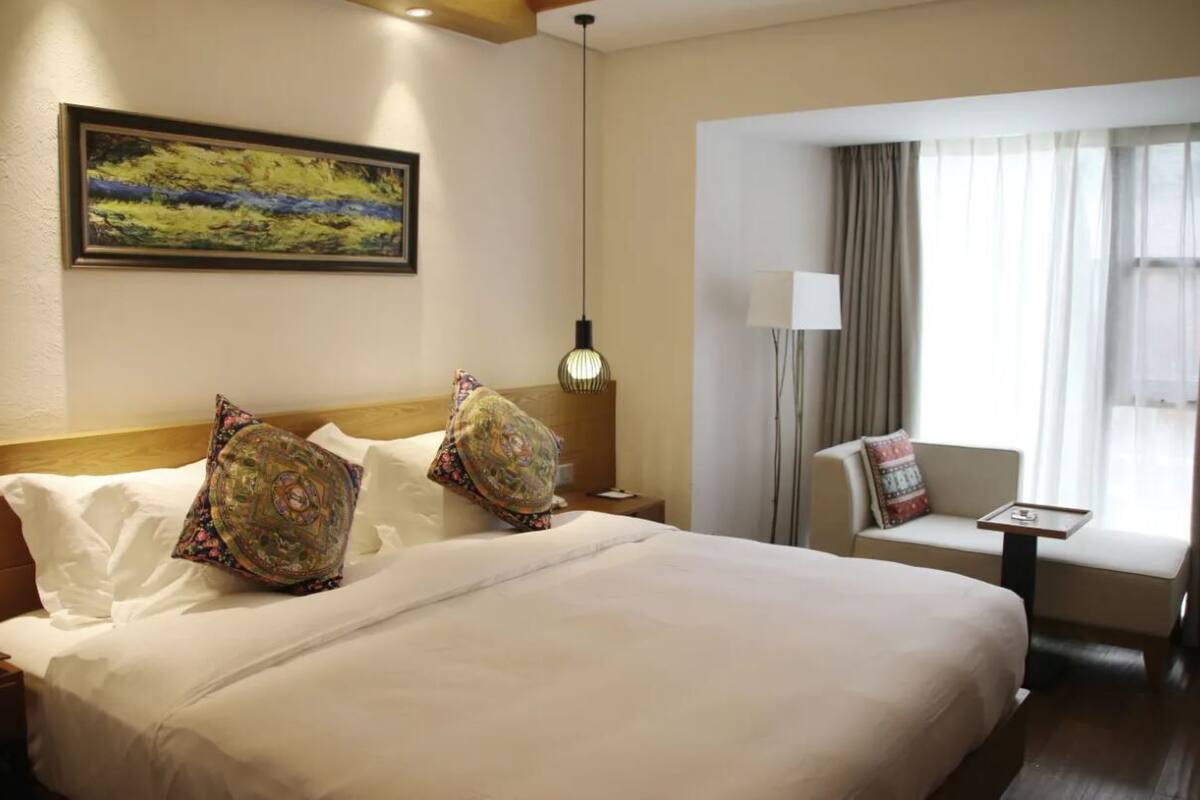 Une chambre d’hôtel avec un grand lit, un canapé, un bureau et une fenêtre avec des rideaux.