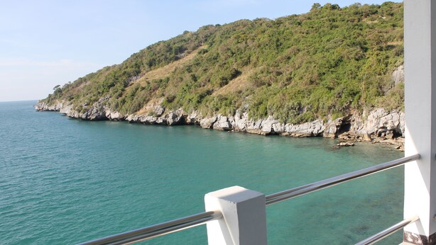 A coastal view with a rocky hillside and clear turquoise water. - Koh Sichang Unseen (Ko Sichang)