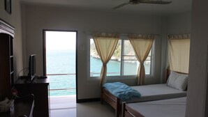 A bedroom with a bed, a desk, and a view of the sea. - Koh Sichang Unseen (Ko Sichang)