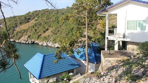 A coastal building with a blue roof, situated on a hillside overlooking a body of water. - Koh Sichang Unseen (Ko Sichang)