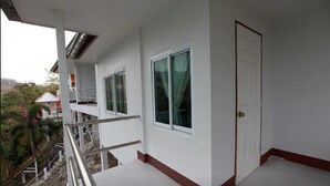 A balcony with a metal railing, a white door, and a window with a curtain. - Koh Sichang Unseen (Ko Sichang)