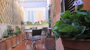 An outdoor patio with terracotta-tiled flooring, potted plants, and outdoor furniture. - Trevi Elegance Suite (Rome)