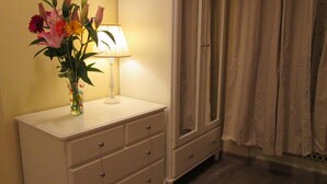 A room with a white dresser, a vase of flowers, a lamp, and a mirror. - Trevi Elegance Suite (Rome)