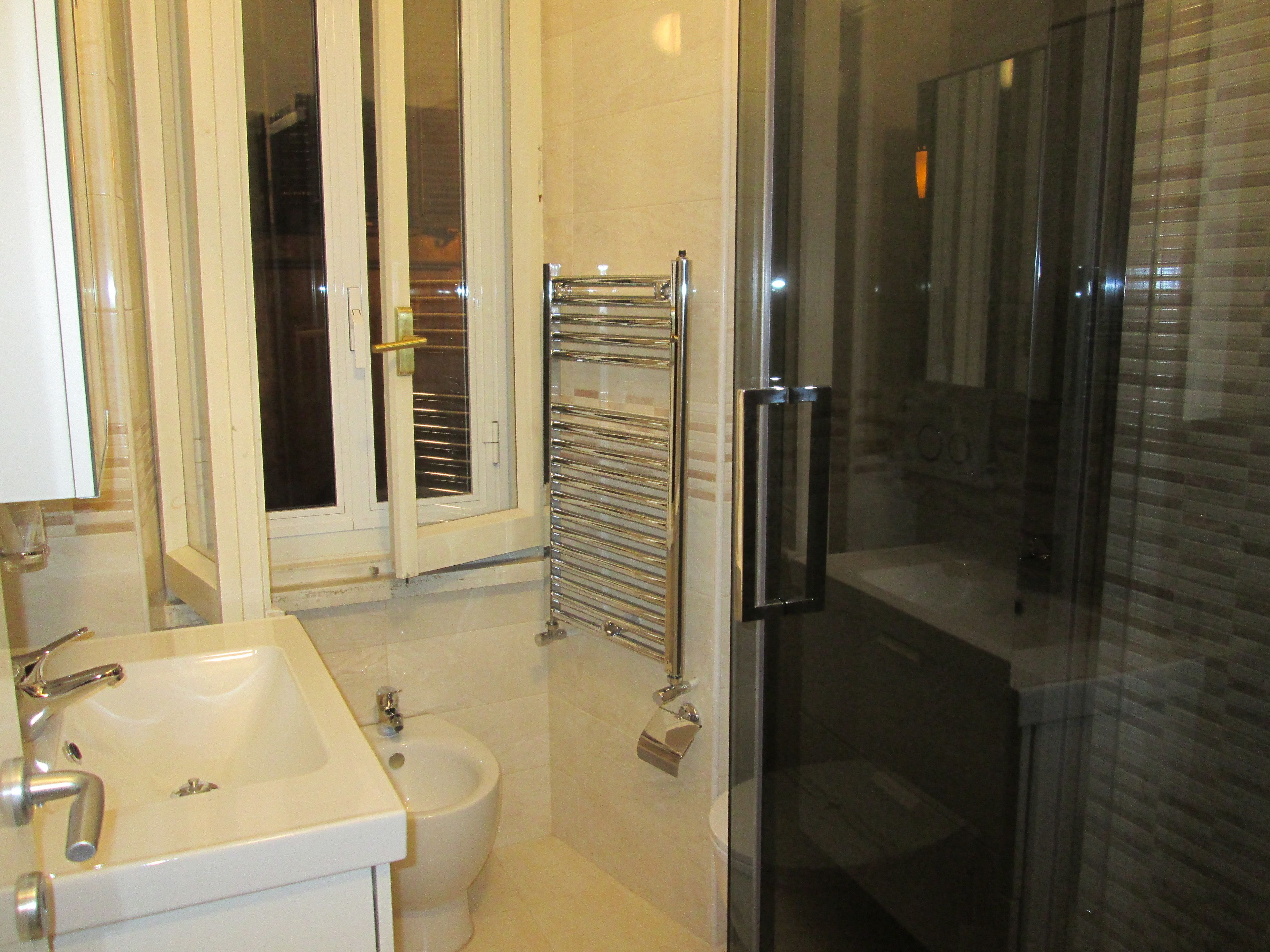 A modern bathroom with a glass shower enclosure, a white sink, and a bidet.