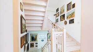 A staircase with white railings and a light blue wall adorned with framed pictures.