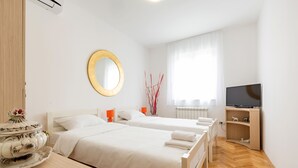 A hotel room with two beds, a TV, a wooden dresser, and a large mirror.