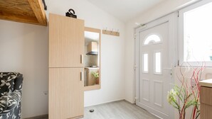 A modern kitchen with a wooden cabinet, a built-in oven, and a white door.