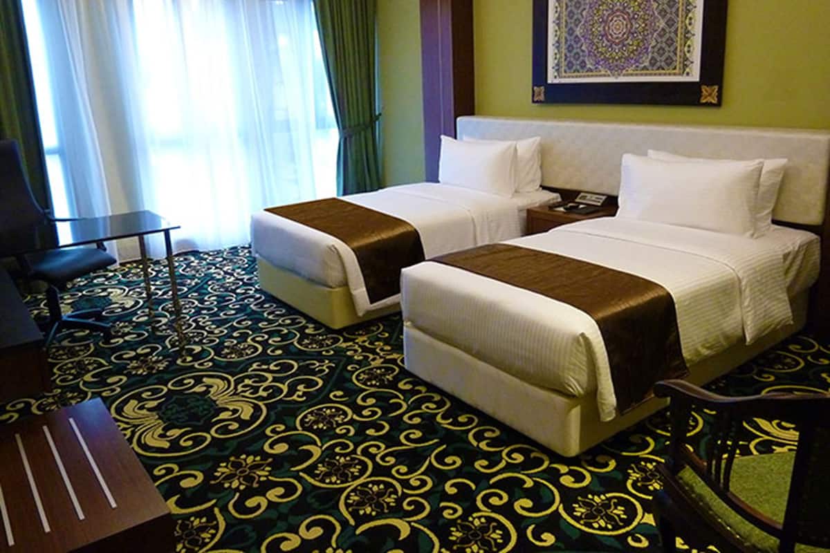 Habitación de hotel con dos camas, un escritorio y una silla.