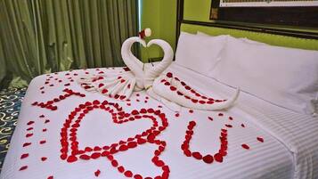 Een bed met een hartvormige bloemstuk van rozenblaadjes en een zwaan-vormige handdoek.