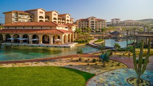 Un complejo turístico con varias construcciones, una piscina central y zonas ajardinadas con cactus.