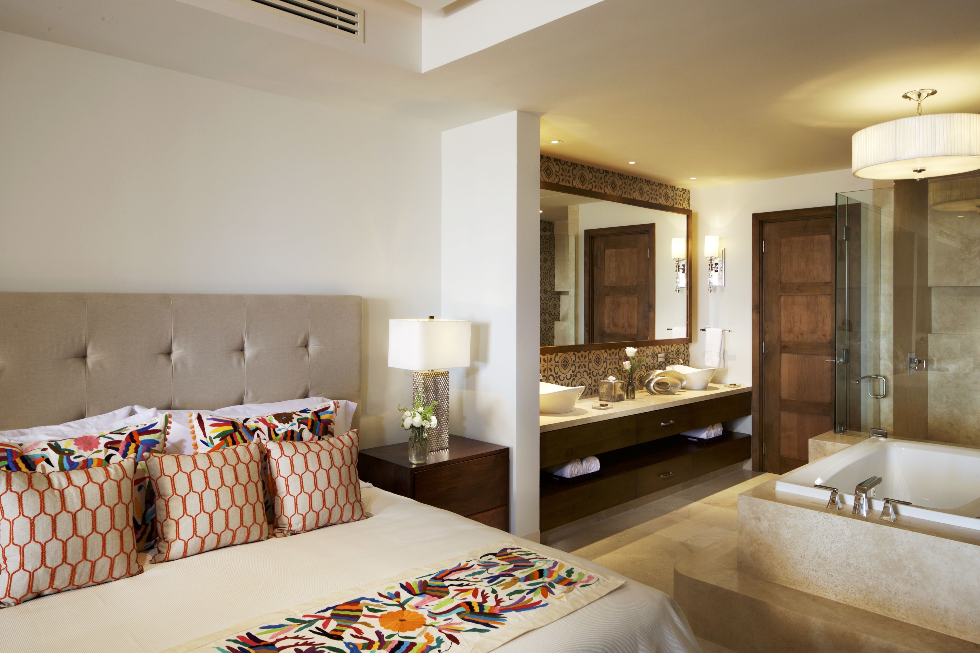 A hotel room with a large bed, a bathroom with a bathtub, and a vanity with a mirror.