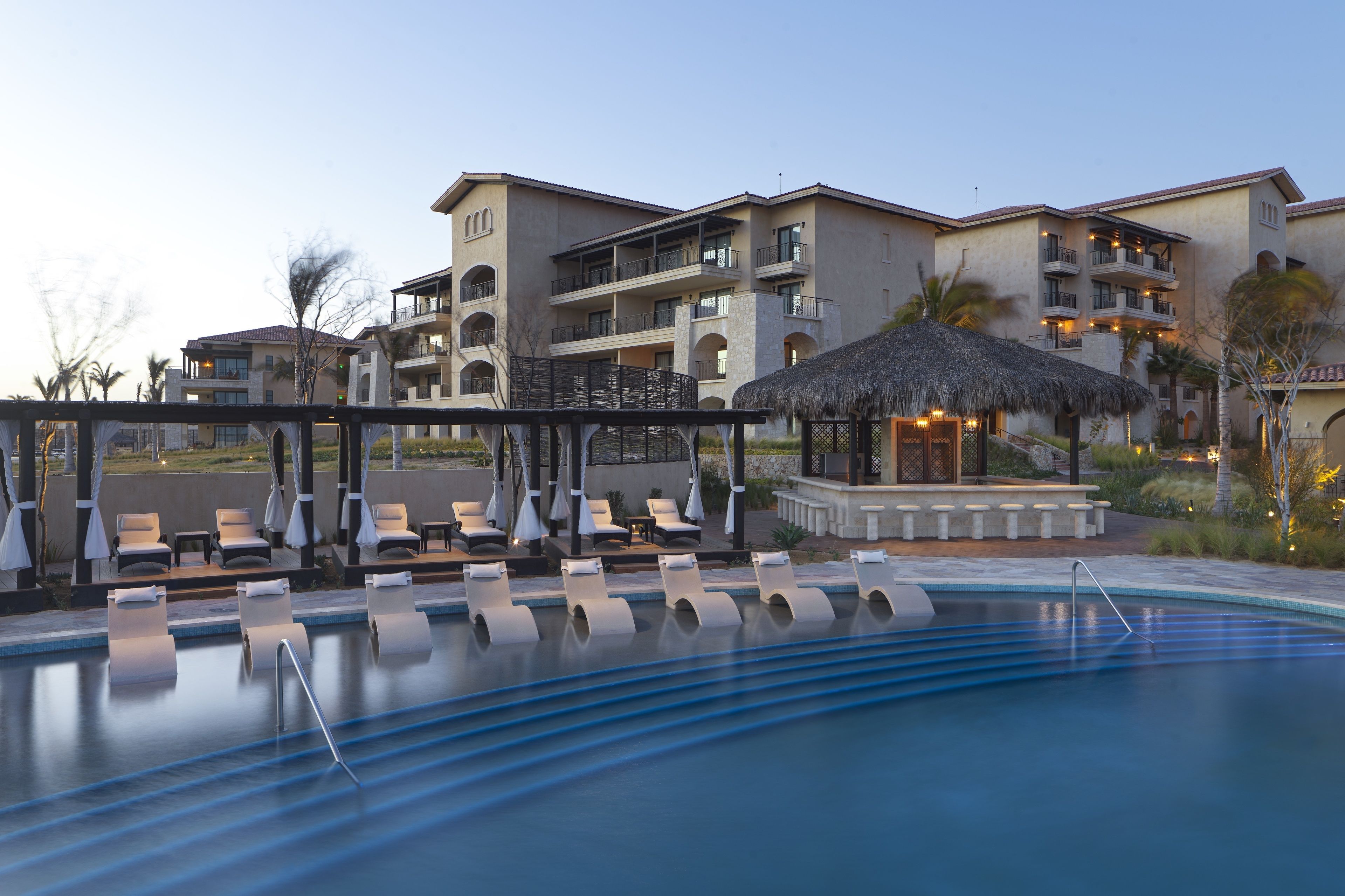 A pool area with lounge chairs and a thatched-roof structure.