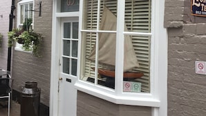 Een hoekpand met een witte deur en luiken, een hangplant en een rookvrij bord.