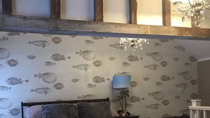 Een slaapkamer met een bed, een nachtkastje met lamp en een muur met vismotieven.