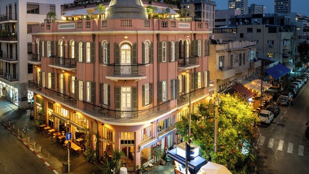 Un hôtel à plusieurs étages, doté d’un dôme central, de balcons et d’un espace extérieur aménagé pour s’asseoir.