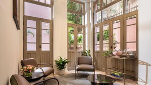 Une pièce spacieuse avec deux fauteuils en cuir, une petite table et une table basse. On y trouve une plante en pot et un chariot en métal sur lequel sont posés un bol et un livre.