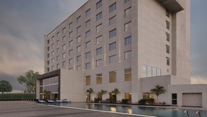 A modern hotel building with a pool area, multiple floors, and a clear sky. - Mercure Chennai Sriperumbudur Hotel (Sriperumbudur)