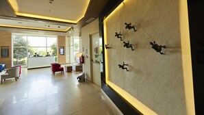 A spacious lobby with a reception desk, seating area, and a wall-mounted sculpture. - Mercure Chennai Sriperumbudur Hotel (Sriperumbudur)