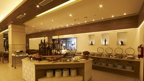 A buffet area with a central serving counter, multiple food stations, and a seating area with tables and chairs. - Mercure Chennai Sriperumbudur Hotel (Sriperumbudur)