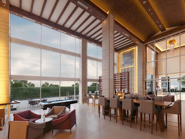 A spacious indoor area with a pool table, multiple seating arrangements, and large windows offering views of the outdoors.