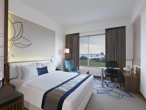 A hotel room with a large bed, a desk, a chair, a lamp, and a view of the outdoors. - Mercure Chennai Sriperumbudur Hotel (Sriperumbudur)