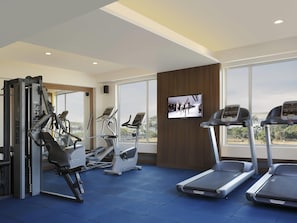 Un gimnasio con cintas de correr, elípticas y equipo de pesas.