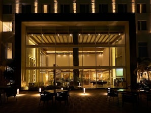 A modern building with large glass windows, a brick patio with outdoor seating, and a visible interior with a pool table. - Mercure Chennai Sriperumbudur Hotel (Sriperumbudur)