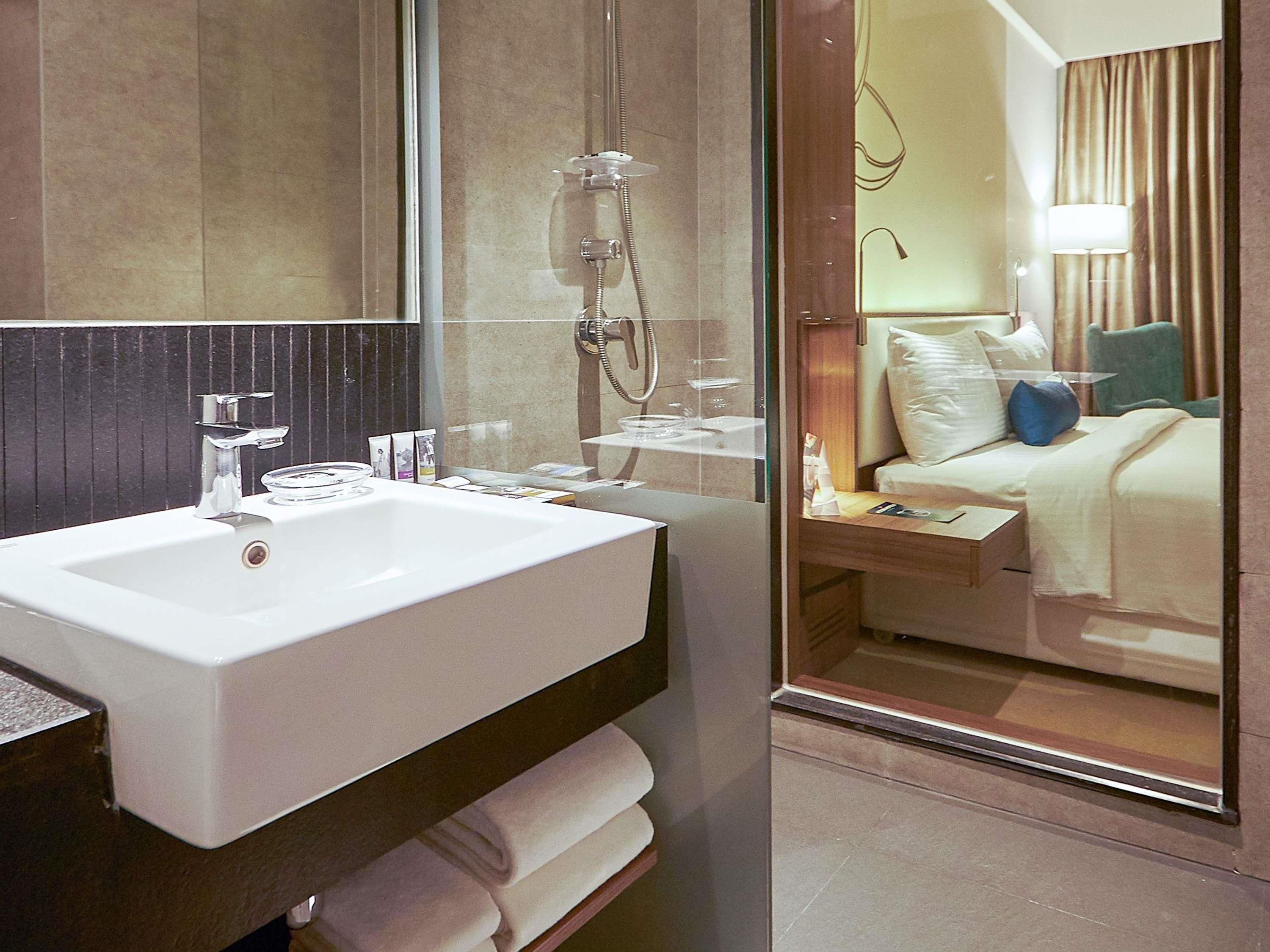 A hotel bathroom with a large sink, mirror, and shower.