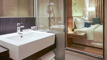 A hotel bathroom with a large sink, mirror, and shower.